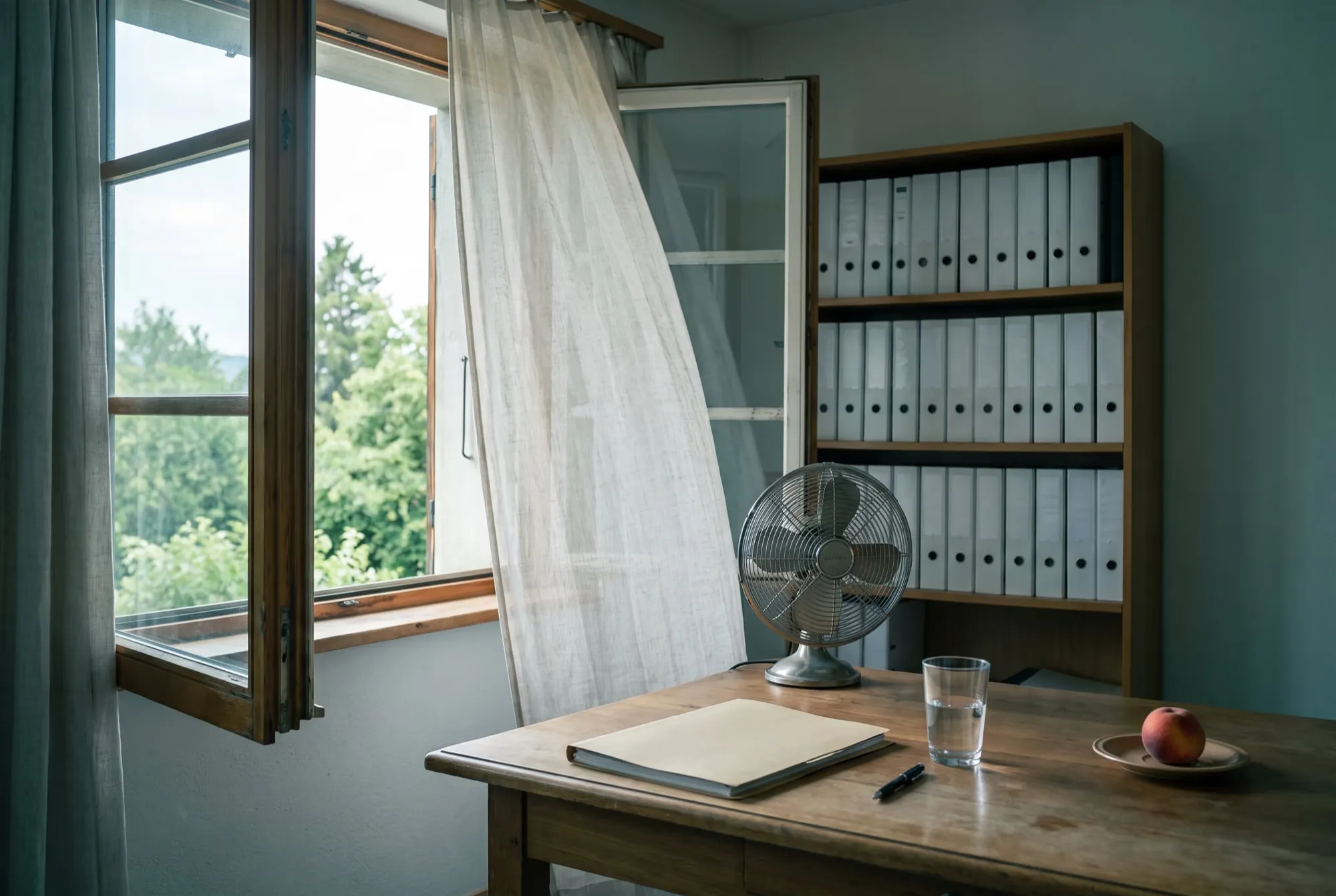 Büro im Sommer mit offenem Fenster, wehendem Vorhang, Ventilator, Mappe und Ordnerregal